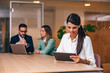 © bnenin - Businesswoman working over the tablet, sitting in the meeting room with two colleagues.