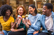 © unai - Multi-ethnic friends in an ice cream parlor sitting eating an ice cream, summer, showing off the ice creams