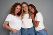 © gpointstudio - Portrait of three young caucasian women wearing blue jeans and white tshirt on grey background