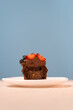 Chocolate cupcakes with berriers and chocolate frosting on white plate. Blue background. Fresh muffin. Vertical frame.