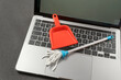 Laptop cleaning concept. Small toy shovel and mop on laptop keyboard. Online cleaning service