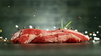 Wall Mural - Flying piece of raw beef steak falling on table. Spice falling with steak. Camera in fast motion. Filmed on high speed cinema camera Phantom VEO 4k, 1000 fps. Placed on high speed cine bot.