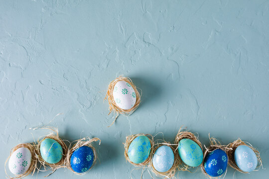Fototapete - Row of hand painted Easter eggs on blue concrete background. Flat lay, top view with copy space