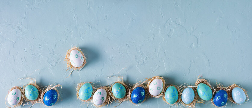 Fototapete - Row of hand painted Easter eggs on blue concrete background. Panorama, banner, flat lay, top view with copy space