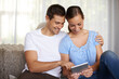 © Daniel Laflor/peopleimages.com - Hes better at this than I am. A cropped shot of an affectionate young couple using a tablet in their living room.