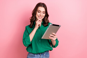 Sticker - Photo of minded intelligent smart woman with wavy hairdo dressed green shirt look at tablet choose product isolated on pink background