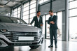 © standret - Talking about automobile. Man is consulting the customer in the car showroom