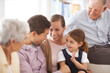 © Mapodile/peopleimages.com - Were one big happy family. Portrait of a smiling three-generational family sitting on the sofa at home.