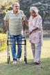 © G-images - Senior couple walking with walker in the park