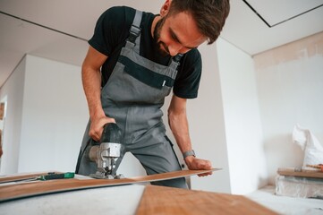 Wall Mural - On the table. Cutting planks by the drill. Man is installing new laminated wooden floor