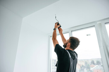 Wall Mural - Installing lighting equipment on the ceiling. Man is working indoors at domestic room