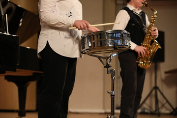 Wall Mural - Young musicians play the drum and saxophone at a school concert standing on stage