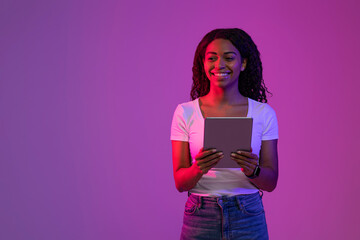 Poster - Smiling Black Woman With Digital Tablet In Hands Standing In Neon Light