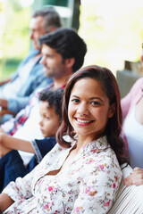 Poster - Enjoying a day spent with her family. A smiling young woman looking at the camera while sitting with her family.