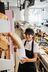 Wall Mural - Beautiful young and happy female worker working in a modern bakery or fast food restaurant.