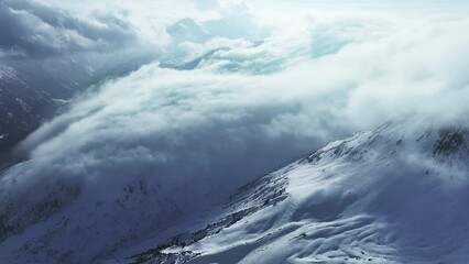 Wall Mural - Alpine landscape with peaks covered by snow and clouds. Magical clouds covering peaks of the mountains at the famous St. Anton am Arlberg ski resort.