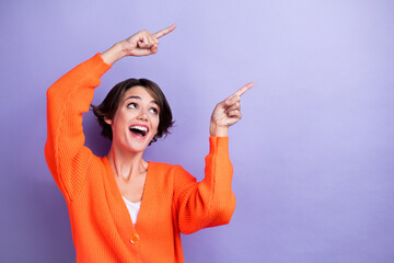 Wall Mural - Photo of positve lovely lady wear stylish orange clothes two arm above head presenting empty space isolated on purple color background