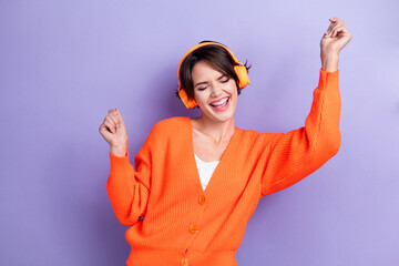 Poster - Photo of cheerful positive lady wear orange trendy clothes eyes closed raised hands good mood isolated on purple color background