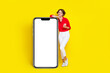 Full size portrait of cheerful nice girl hold telephone empty space poster isolated on yellow color background