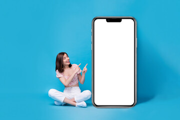 Wall Mural - Photo of cute stylish lady sit look hand demonstrate recommend use buy telephone empty space promo isolated on blue color background