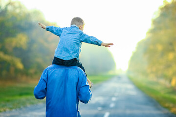 Wall Mural - A Happy parent with child are walking along the road in the park on nature travel