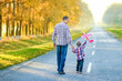 © Kostia - A Happy parent with child are walking along the road in the park on nature travel