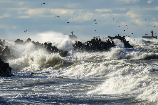 coastal storm in the baltic sea, big waves crash against the harbor breakwater, breaking wave