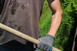 Dirty worker holds a shovel in his  hands under the scorching sun