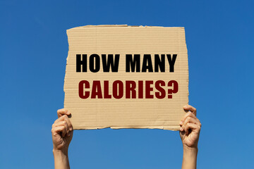 How many calories text on box paper held by 2 hands with isolated blue sky background. This message board can be used as business concept about calories.