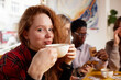 © Georgii - Multiethnic company of young people drinking coffee and playing games, looking at smartphones, taking selfies.