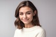 © Adriana - Beautiful smiling brunette woman wearing a white sweater on white background, looking at the camera. Generative AI