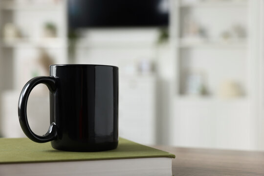 Wall Mural - Blank ceramic mug and book on wooden table. Mockup for design