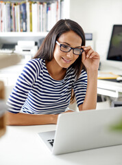 Poster - Things are looking good for her business. a beautiful young woman using her laptop in her home office.