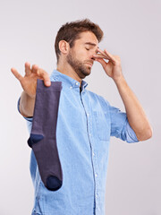 Poster - Keep this sock away from me. Studio shot of a handsome young man holding an unpleasant smelling sock against a gray background.