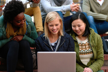 Sticker - Uploading their assignments. a group students looking at a laptop on campus.