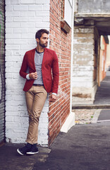 Wall Mural - He brings class to the streets. a handsome young man leaning and posing against a wall in the city while touching his jacket with one hand.