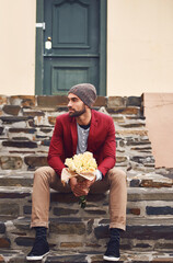 Wall Mural - Now all we do is wait for her. a handsome young man seated on steps outside in the city holding a bunch of flowers waiting for someone.