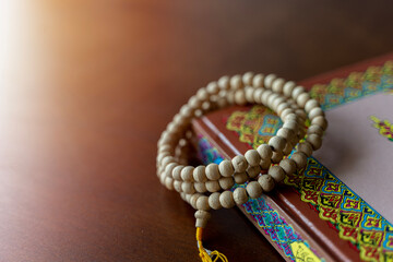 Holy Islamic Book Koran with rosary beads on wooden background. Quran with written Arabic calligraphy meaning of Al Quran. Ramadan Mubarak.