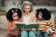 Family kids, book and grandma reading fantasy storybook, story or bonding on home living room sofa. Grandmother love, novel and elderly woman with child development for biracial kindergarten children