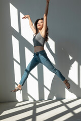 Wall Mural - Asian dancer girl makes an acrobatic jump illuminated by the sun that enters through the window in an empty building. isolated