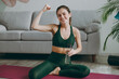 © ViDi Studio - Full body happy young strong sporty athletic fitness trainer instructor woman wear green tracksuit drink water show muscles training do exercises at home gym indoor Workout sport motivation concept.