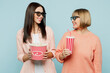 © ViDi Studio - Smiling elder parent mom with young adult daughter two women together in 3d glasses watch movie film hold bucket of popcorn cup of soda pop in cinema isolated on plain blue background studio portrait.