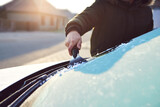 Fototapeta Sypialnia - A man scratches the front window of his car on a cold winter morning