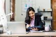 © Katcha - Young businesswoman in suit is reading business data on laptop a