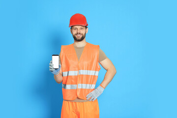 Canvas Print - Man in reflective uniform showing smartphone on light blue background