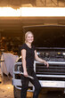 © Austockphoto - Young female aussie mechanic leaning on a car in need of repair in workshop holding a wrench