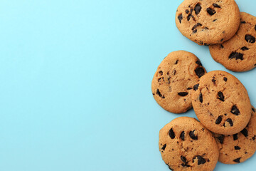 Many delicious chocolate chip cookies on light blue background, flat lay. Space for text