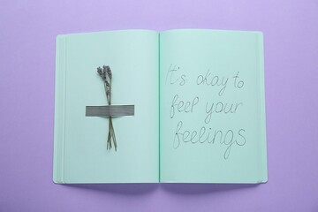 Wall Mural - Phrase It`s Okay to Feel Your Feelings and dry lavender attached with adhesive tape in notebook on violet background, top view