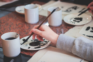 Chinese calligraphy lesson, group of kids learn and practicing traditional calligraphy in class, kid black with ink and brush learn writing of chinese characters in school