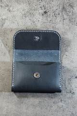 Black leather cardholder on a gray background. Handmade leather products.